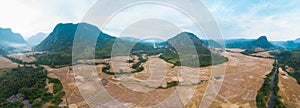 Aerial panoramic Muang Ngoi Laos river valley yellow ripe rice fields agriculture dramatic landscape scenic pinnacle cliff