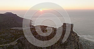 Aerial panoramic shot of famous tourist attraction at sunset. Backwards reveal of flat top of Table Mountain. Cape Town