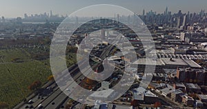 Aerial panoramic shot of large city. Busy multilane expressway leading along cemetery. Downtown skyscrapers in distance