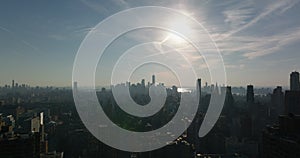 Aerial panoramic shot of large city. Silhouettes of downtown skyscrapers against sun. Manhattan, New York City, USA