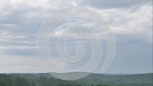 aerial panoramic time lapse of summer rain over the green forest and white clouds running on the blue sky. View from the top of t