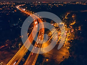 Aerial panoramic view from above to night city with bridge, road with car traffic and parking for automobiles, drone photo