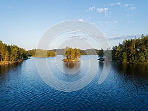 Aerial panoramic view of beautiful calm lake at sunset surrounded by forests.