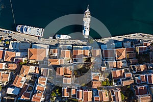 Aerial panoramic view on beautiful Greek houses on island hills, yacht sea port, tourist ferry boat at Aegean Sea bay. Greece