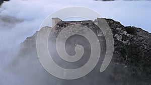 Aerial panoramic view of a beautiful medieval Castle standing out of the fog on a misty winter morning.