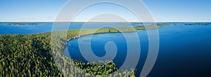 Aerial panoramic view of blue lake with islands and green forest in Finland.