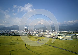 Aerial panoramic view of a factory with smoking chimneys by green rice paddies in Yilan Ilan photo