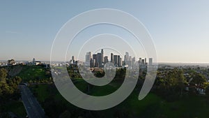 Aerial panoramic view of green vegetation in city and skyline with famous downtown skyscrapers against clear sky. Los