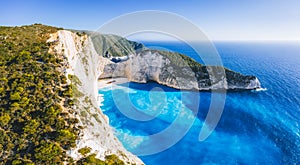 Aerial panoramic view of Navagio Beach - Shipwreck beach - on Zakynthos Island, Greece. Tourists on cliff edge enjoy