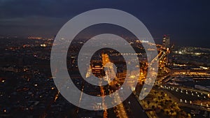 Aerial panoramic view of night metropolis. Traffic on illuminated trunk road leading along waterfront. Barcelona, Spain