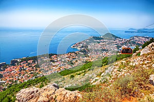 Aerial panoramic view of the old town of Dubrovnik with famous Cable Car on Srd mountain on a sunny day