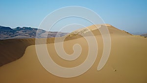 Aerial panoramic view sand dunes contrasts with mountains in wild nature.