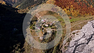 Aerial panoramic view of a small mountain village with old houses. Footage. Green and yellow autumn trees growing on one