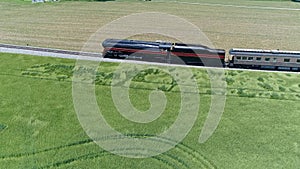 Aerial Parallel View of an Antique Steam Passenger Train Traveling Thru Farmlands on a Sunny Day