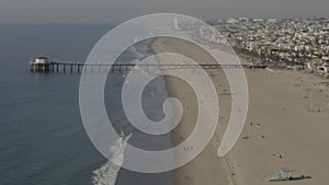 AERIAL: People at the Beach Waves,Water with Pier in Los Angeles, California, Sunny, Blue Sky