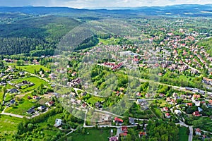 Aerial perspective view on sudety mountains with touristic city in the valley surrounded by meadows, forest and rapeseed fields photo