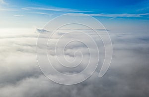 Aerial photo above the fog or white clouds with shining sun. Beautiful sunrise cloudy sky from aerial view. Above clouds from