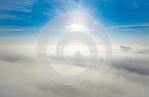 Aerial photo above the fog or white clouds with shining sun. Beautiful sunrise cloudy sky from aerial view. Above clouds from