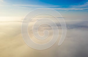 Aerial photo above the fog or white clouds with shining sun. Beautiful sunrise cloudy sky from aerial view. Above clouds from