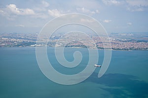 Aerial photo from airplane showing Istanbul cityscape with ocean water, coast, ships, buildings and sky background