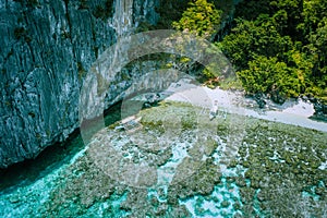 Aerial Photo of banca boats moored at white sand paradise beach and people snorkeling over colorful coral reefs in El