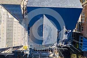 Aerial photo of building construction work being done on a property with scaffolding up at the property and roofers working on the