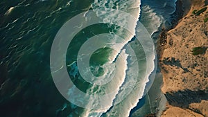 This aerial photo captures the forceful meeting of the ocean waves with the rugged cliffs, An aerial view of waves approaching the