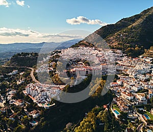 Aerial photo distant view charming Mijas pueblo, typical Andalusian white-washed mountain village, houses rooftops, small town