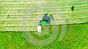 Aerial photo farm scene agricultural tractor mows grass with a mower in the farm fields, haymaking