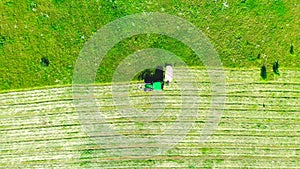 Aerial photo farm scene agricultural tractor mows grass with a mower in the farm fields, haymaking