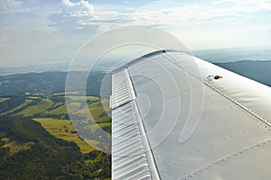 Aerial photo of landscape with fields, meadows and forests with a small airplane wing in foreground