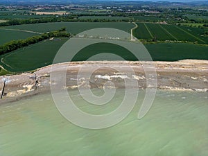 Aerial photo of a lush green grassy field with a beach shoreline in the background