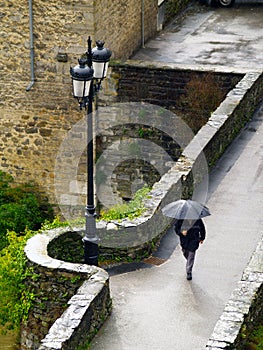 Aerial photo of a medieval bridge and a person with an umbrella