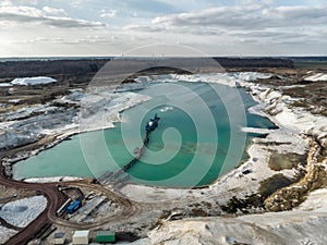 Aerial photo of one of the quartz quartz quartz quarry mining ponds with a suction dredger in the foreground and a dramatic sky.