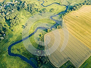 Aerial Photo the River Flowing Between Yellow and Green Agriculture Fields in Early Spring on Sunny Day