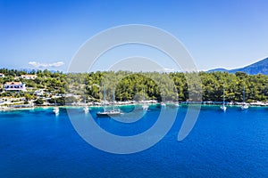 Aerial photo of sailing boats docked in blue bay of Fiskardo, Kefalonia island, Ionian, Greece