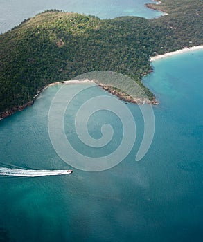 An aerial photo of a small speedboat and one of the islands in Whitsundays in Australia