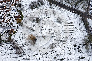 Aerial photo of a snowy day in the city of Leeds in the UK showing a snow filled grave yard cemetery with bar trees and snow