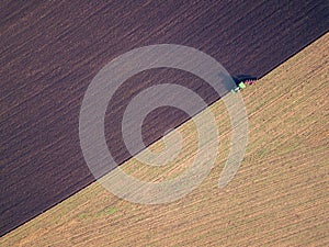 Aerial photo of a tractor ploughing a field in a countryside