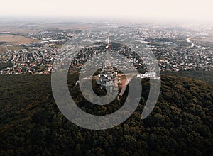 Aerial photo of transmitter tower on Zobor Hill in Nitra - Slovakia. Flight by drone over the hill and large city near forest