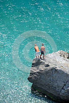 Aerial photo of two young boys on rock looking into sea