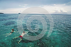 Aerial photo of young couple on holidays swimming in ocean