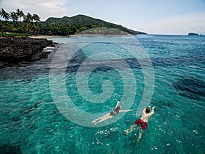 Aerial photo of young couple on holidays swimming in ocean