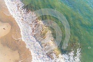 aerial photograph with zenithal sunrise view of a beach with turquoise sea waves crashing on the shore photo