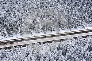 aerial photography of snowy forest and city road with tramway rails