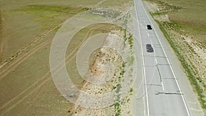 Aerial photography of traveling girl with backpack on an asphalt road on sunny day among the mountains. Panoramic view