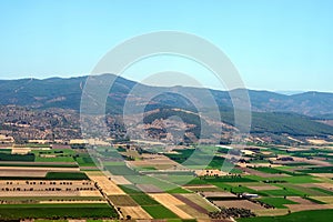 Aerial photography. View from the plane`s window: mountains on the horizon, green fields and meadows below.