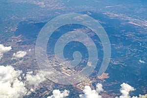 Aerial photography. View from the plane window: flying above the clouds, below you can see mountains and green fields.