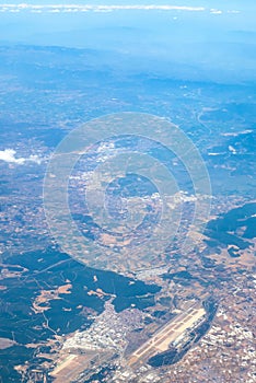 Aerial photography. View from the plane window: from a great height below you can see mountains and green fields.