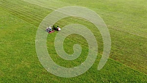 Aerial photography. Wide and close-up shots of a harvester cutting green grass. Birds of prey swirl over cars. The concept of sust